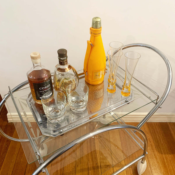 Australian art deco chrome and glass bar cart with bakelite wheel skirts