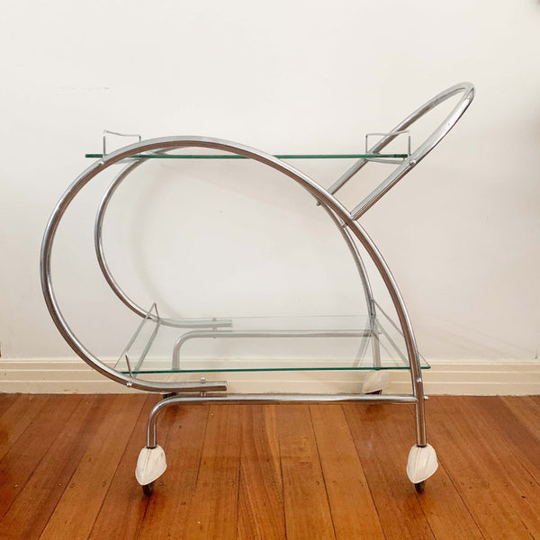 Australian art deco chrome and glass bar cart with bakelite wheel skirts