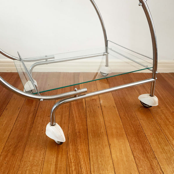 Australian art deco chrome and glass bar cart with bakelite wheel skirts