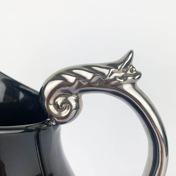 Silver scroll handle close up on ceramic pitcher