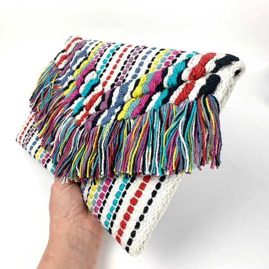 Embroidered cotton multi coloured clutch held in hand to indicate size